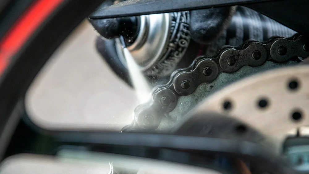 membersihkan rantai motor dengan degreaser dan sikat khusus rantai